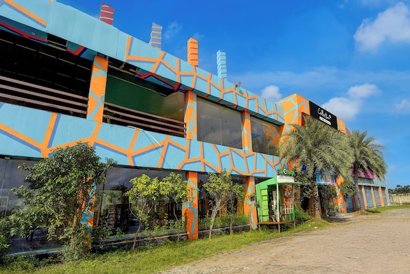 A colorful building with a geometric pattern, a green structure labeled 'Oil Charge,' and a palm tree. - Collection Sirkazhi Formerly Navagiragat (Chennai)