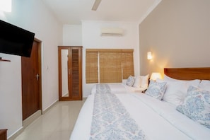 A hotel room with a bed, a wardrobe, a mirror, and a window with blinds. - Hotel TravllersNest Kandy (Kandy)