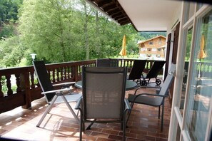 A balcony with a table and chairs, a view of trees, and a building in the background. - Holiday apartment with 2 bedrooms (Bad Wiessee)