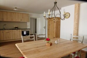 A dining area with a wooden table, chairs, a chandelier, and a clock on the wall. - Holiday apartment with 2 bedrooms (Bad Wiessee)