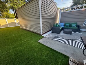 A backyard with artificial grass, a patio area with outdoor furniture, and a shed. - Salt and Sand Myrtle Retreat (North Myrtle Beach)