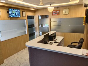 Una recepción con una computadora, un reloj y un televisor mostrando imágenes de seguridad.