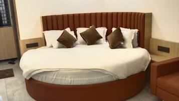 A modern bedroom with a round bed, a brown headboard, and a brown armchair.