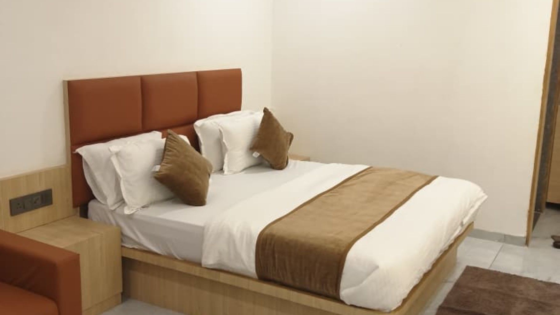 Una cama individual con cabecera, ropa de cama blanca y dos almohadas marrones.