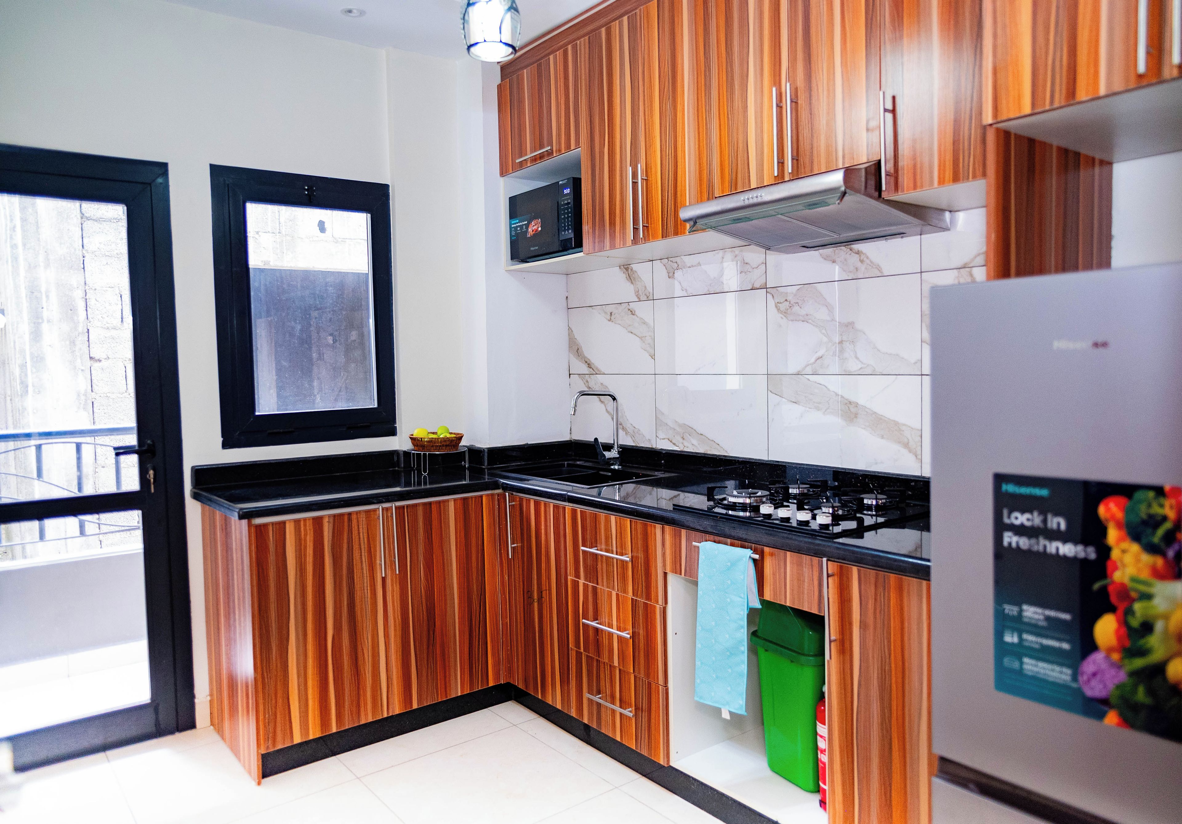 Una cocina moderna con armarios de madera, encimera negra, microondas y estufa a gas.