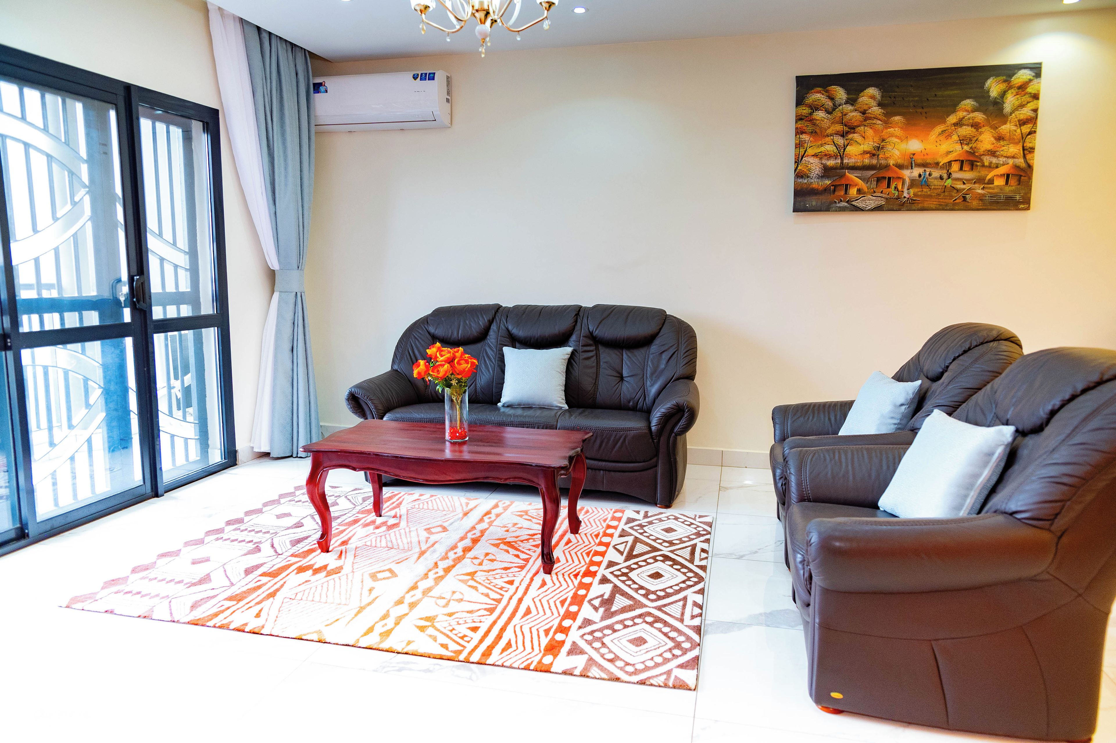 Una sala de estar con un sofá, un sillón, una mesita de centro y un cuadro en la pared.