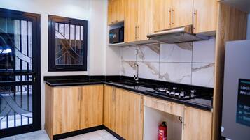 A modern kitchen with wooden cabinets, a black countertop, a microwave, and a gas stove.