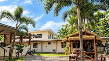 Un complexe hôtelier tropical doté de bungalows aux toits de chaume, de palmiers et d’une cour recouverte de gravier.