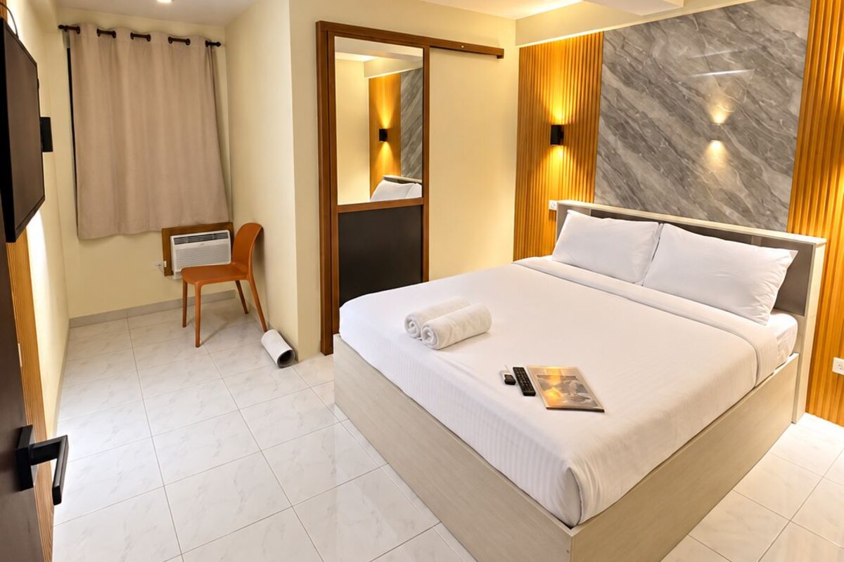 Una habitación de hotel moderna con una cama grande, un escritorio y un espejo.