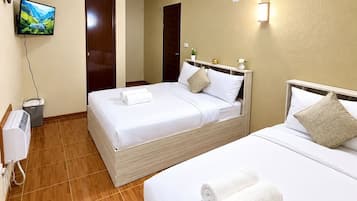 Une chambre d’hôtel avec deux lits, une télévision, un radiateur et une lampe fixée au mur.