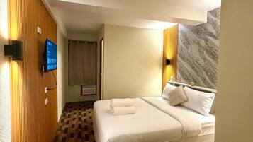 Une chambre d’hôtel avec un lit, une télévision et un mur recouvert de panneaux de bois.