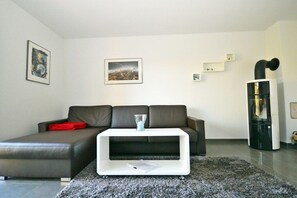 Ein modernes Wohnzimmer mit einer Eckcouch, einem weißen Couchtisch und einem schwarzen Kamin.