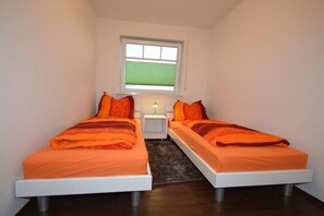 Une petite pièce avec deux lits, une fenêtre et une table de chevet.
