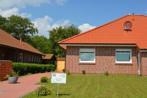 Ein Backsteinhaus mit rotem Ziegeldach, einer Satellitenschüssel und einem Schild, das es als Pension kennzeichnet.