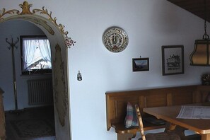 Ein Zimmer mit einer hölzernen Bank, einer an der Wand befestigten Uhr und einem gerahmten Bild.