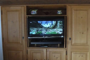 Ein Fernsehgerät an einem Holzkabinett befestigt, darüber mit dekorativen Gegenständen.