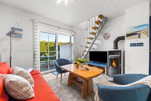 Ein modernes Wohnzimmer mit einem Holztisch, einem blauen Sessel, einem roten Sofa, einer Wendeltreppe und einem Kamin.