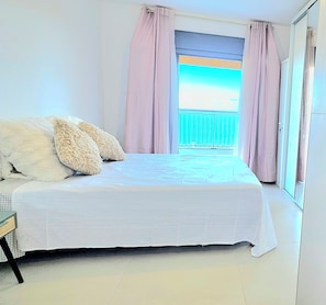 A bedroom with a bed, pillows, a nightstand, and a view of the outdoors through a window. - KAz Bel Horizon welcomes you for a stay on this paradise island. (Saint-Leu)