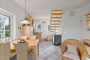 Eine moderne Küche mit einer Holztreppe, einem Essbereich inklusive Tisch und Stühlen sowie einer Rattansofa.