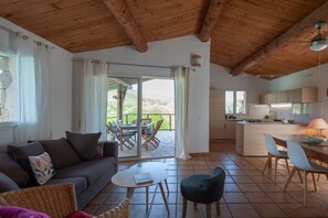 A spacious living area with a sofa, a dining table, and a kitchen area with a counter and cabinets. - Holiday home with 3 bedrooms (Porto Vecchio)