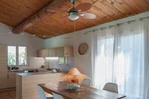 A modern kitchen with wooden ceiling beams, a central island, and a dining area with a table and chairs. - Holiday home with 3 bedrooms (Porto Vecchio)
