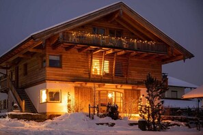 A wooden chalet with a balcony, a staircase, and a snow-covered landscape. - Holiday home with 1 bedroom (Unterwössen)