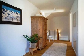 A hallway with a wooden cabinet, a framed picture on the wall, a potted plant, and a small stool. - Holiday home with 1 bedroom (Unterwössen)