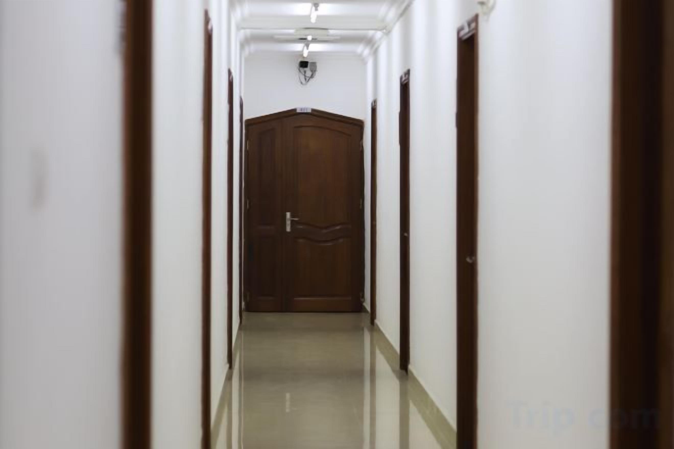 A narrow, well-lit hallway with a wooden door at the end.