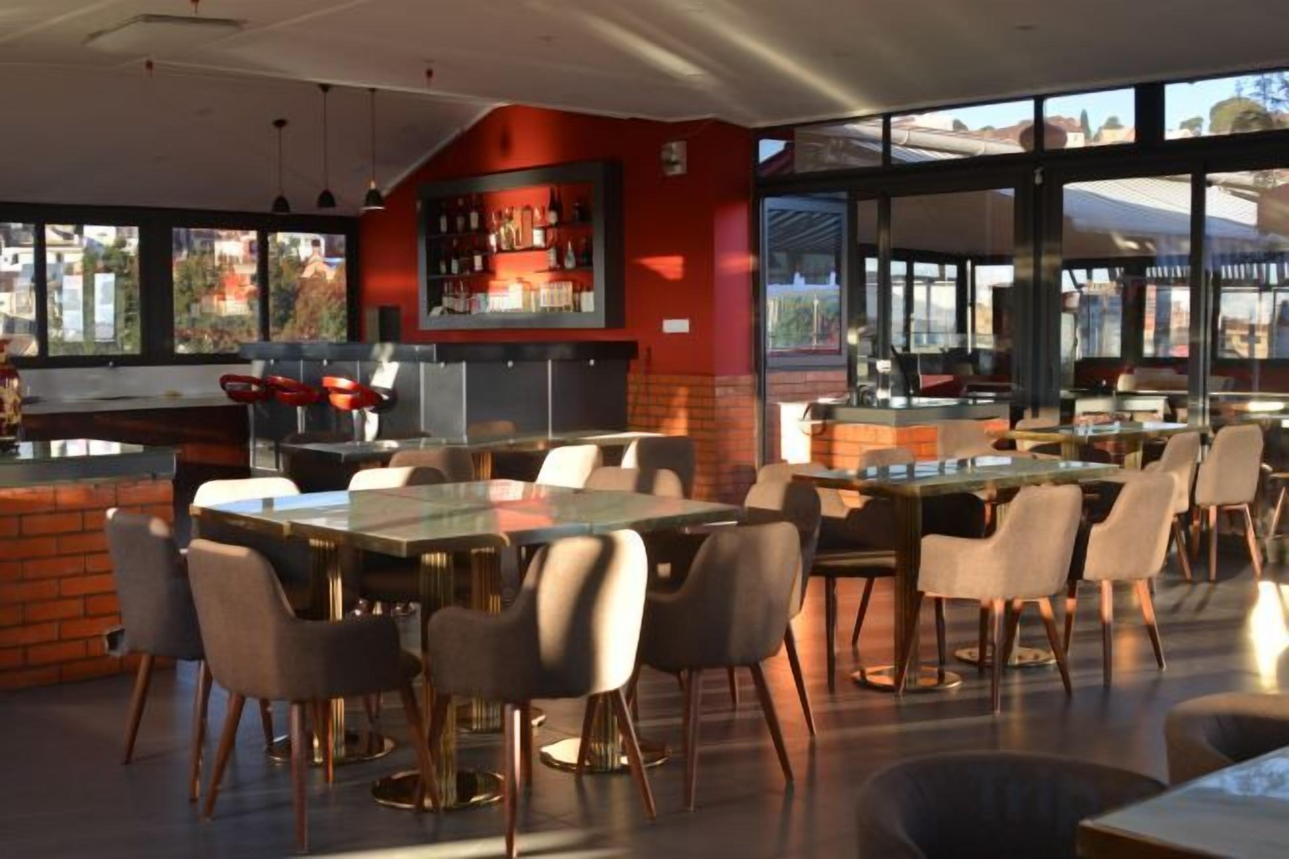 A restaurant with a bar area, tables, and chairs.