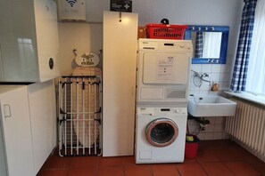 Un área de lavandería compacta con lavadora y secadora apiladas, un tendedero y un lavabo.