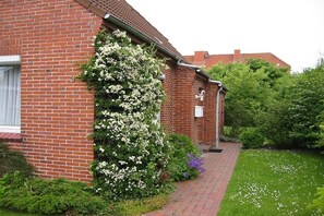 A brick building with a brick pathway leading to a door. - Frisian house on Möwenweg (Norden-Norddeich)