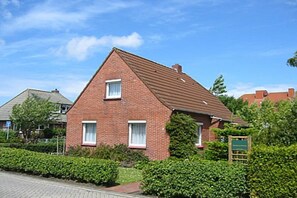 A brick house with a pitched roof, a small window, and a door. - Frisian house on Möwenweg (Norden-Norddeich)