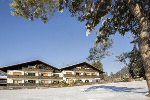 En toetages chalet med altaner, beliggende i et sneklædt landskab.