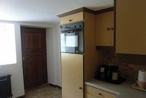 A compact kitchen with a built-in oven, a microwave, and a coffee maker on the countertop. - Domaine du Chasseur Wanzel (Obersteinbach)