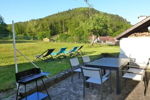 An outdoor patio with a grill, chairs, and a table. - Domaine du Chasseur Wanzel (Obersteinbach)