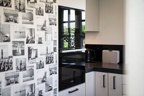 Eine Küche mit einem großen Fenster, einem Bosch-Kühlschrank und einer Krups-Kaffeemaschine.