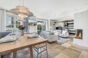 Un interior moderno con comedor, sofás, chimenea y cocina.