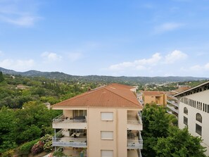Ein mehrstöckiges Wohngebäude mit Balkonen, umgeben von Grün und mit Blick auf Berge.