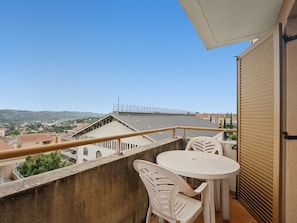 A balcony with a table and chairs, overlooking a cityscape with buildings and hills. - Studio with swimming view and nature view (Grasse)