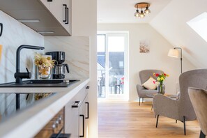 A modern kitchen with a coffee machine, a vase with flowers, and a view to the outside. - Wind force 7/6 - Sauna. Balcony. Vacation on the Baltic Sea. Meernah. (Grömitz)