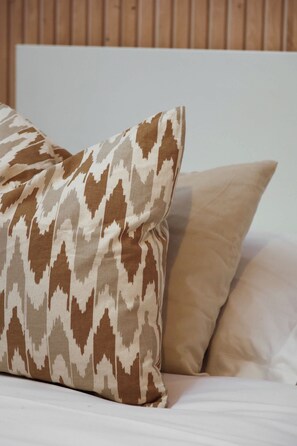 A bed with two pillows, one with a geometric pattern and the other plain. - Chic Studio Near Champs-Elysees & Eiffel Tower (Paris)