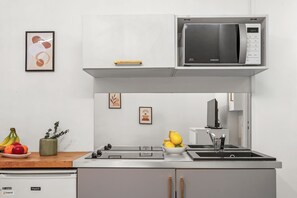 Una cocina moderna con microondas, pileta y frutero.