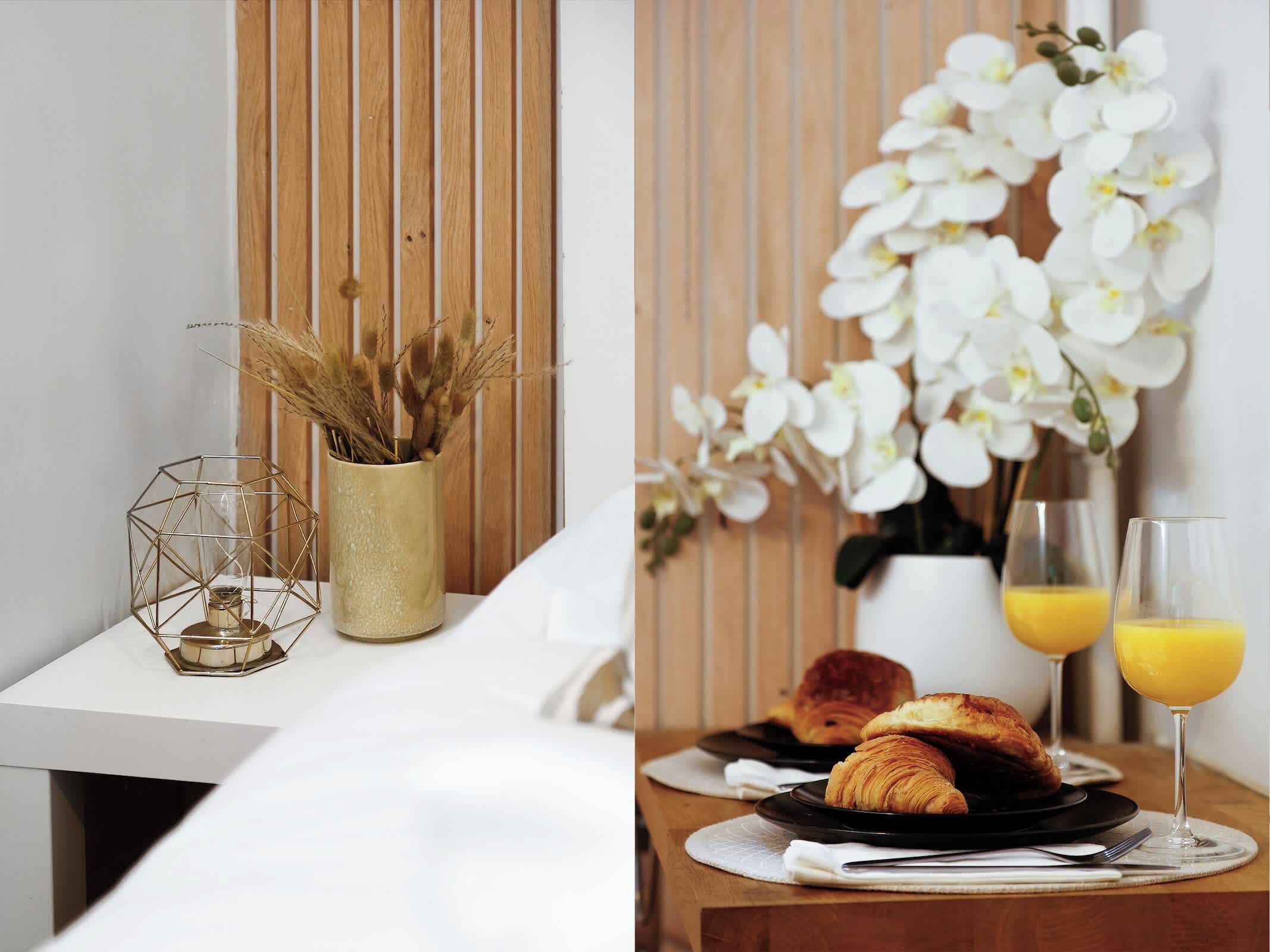 A breakfast setting with croissants, orange juice, and a vase of white flowers.