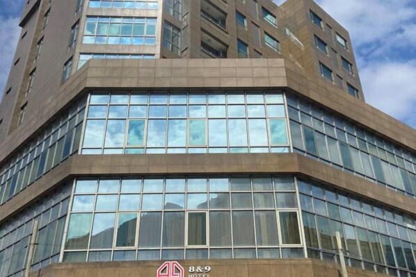 A multi-story hotel with a modern architectural design, featuring large windows and a prominent logo on the facade.