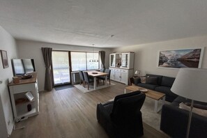 Een moderne woonkamer met een bank, een salontafel en een eethoek met een tafel en stoelen.