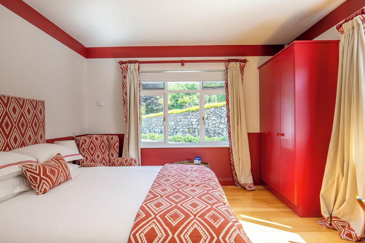 A bedroom with a bed, a wardrobe, and a window with curtains.