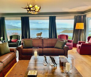A cozy living room with a plaid sofa, a wooden coffee table, and a view of a lake.