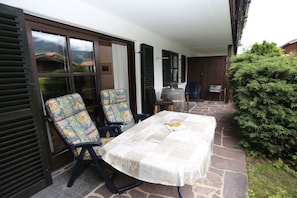 Eine Terrasse im Freien mit einem Tisch, zwei Stühlen, einem Holzfass und einem kleinen Tisch mit einem Stuhl.