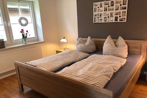 A bed with striped bedding, a bedside lamp, and a wall with a photo collage. - Holiday home with 4 bedrooms (Norddeich)
