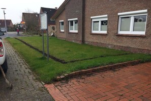 A residential area with a paved driveway, a grassy lawn, and a brick building with windows. - Holiday home with 4 bedrooms (Norddeich)